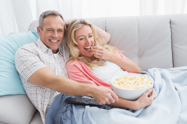 couple on the couch happy eating popcorn