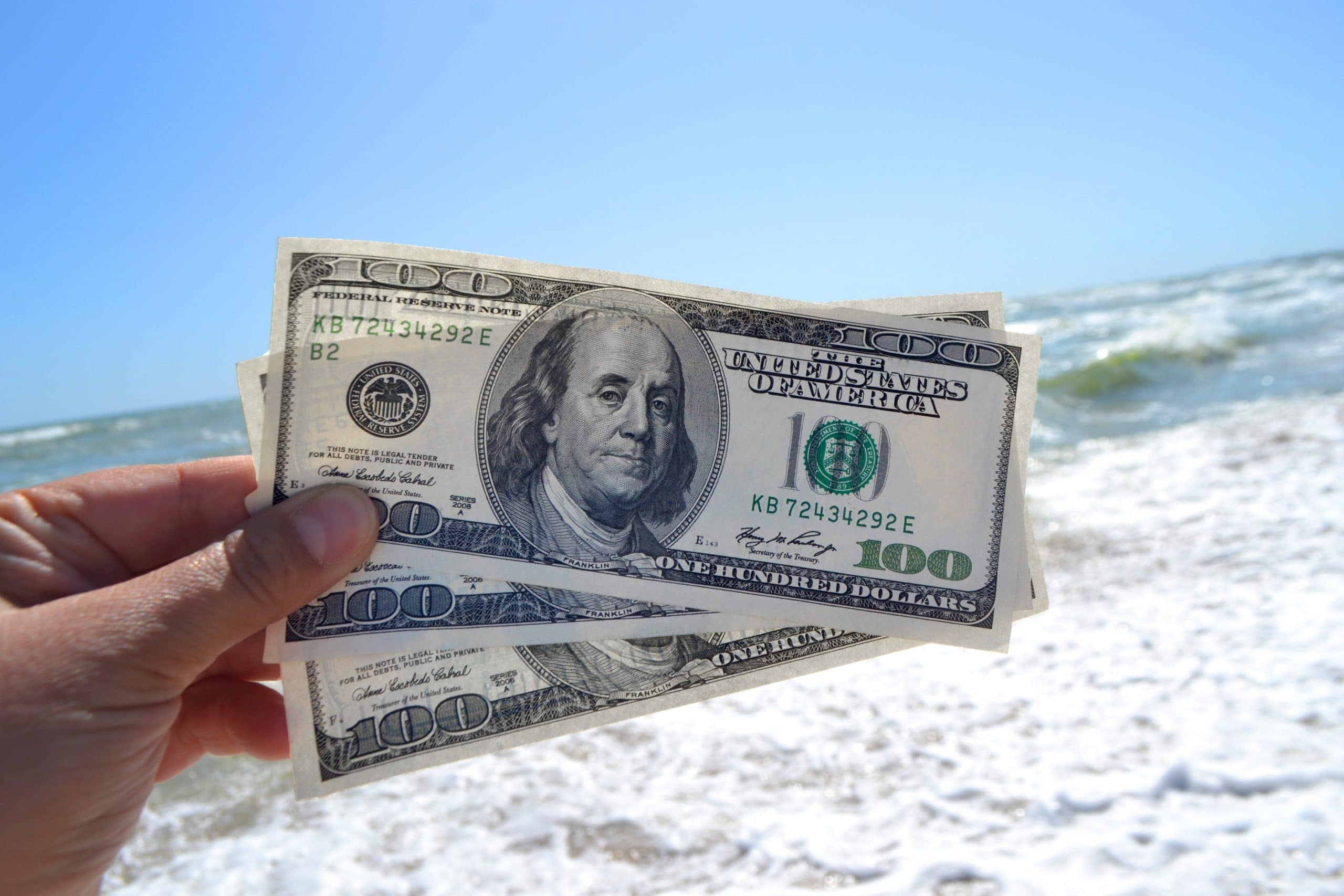 holding $300 at the beach