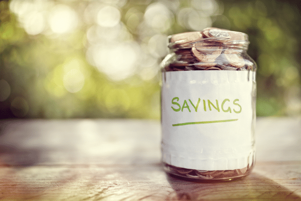 jar of change labeled savings on a table outside