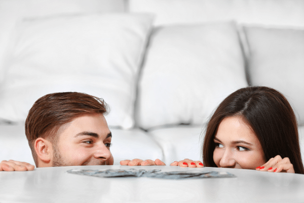 couple peeking over table money