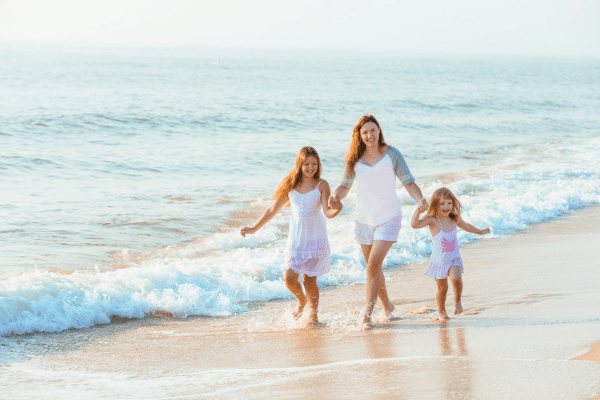 woman and two girls walking on the beach