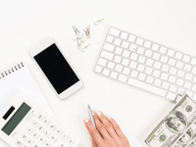 phone,money, keyboard, womans hand holding pen