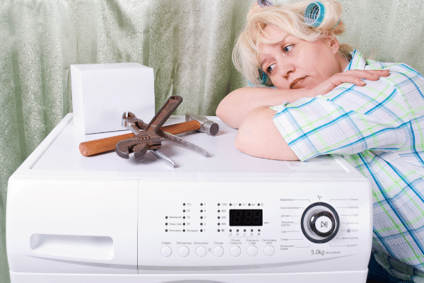 woman leaning on washing machine looking at tools