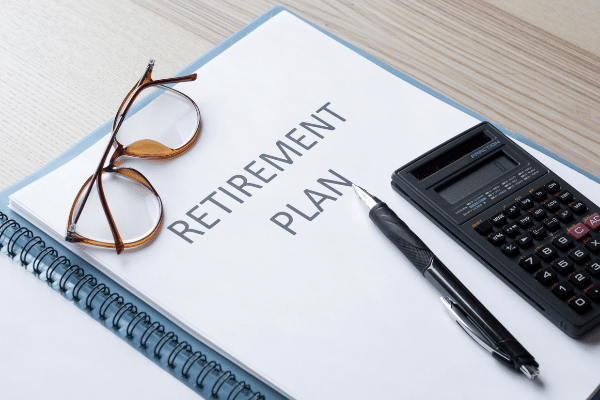 notebook with retirement plan next to calculator and glasses