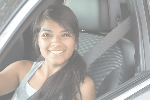 teen girl driving car smiling