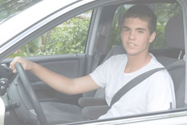 teen boy driving a car smiling