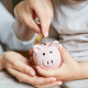 child and adult putting money in piggy bank