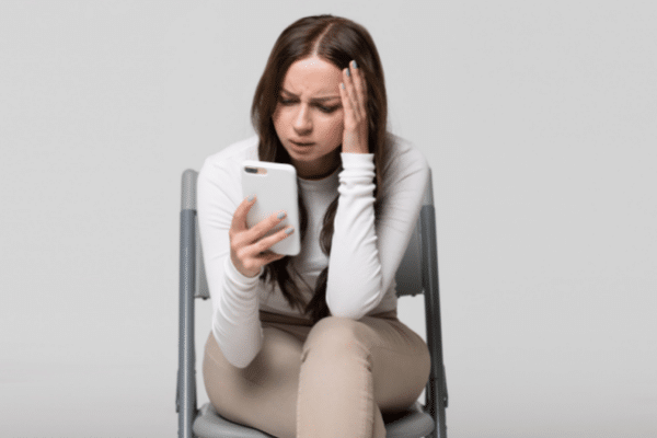 womn in chair upset looking at her phone