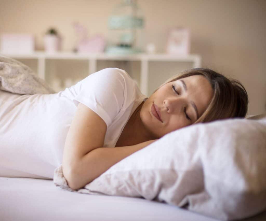 sleeping young woman in white tshirt with her head on pillow
