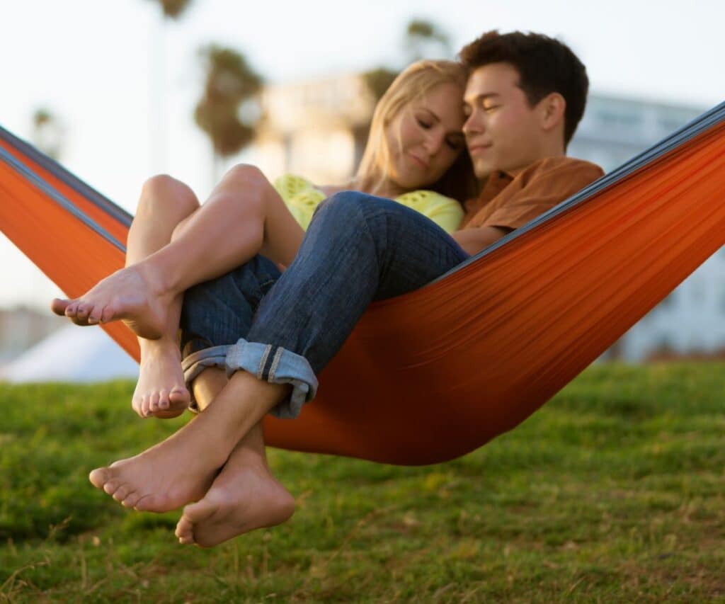 couple enjoying backyard date in an orange hammock hammock