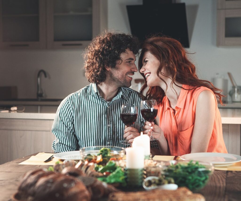 couple enjoying wine during a candlelight dinner date at home