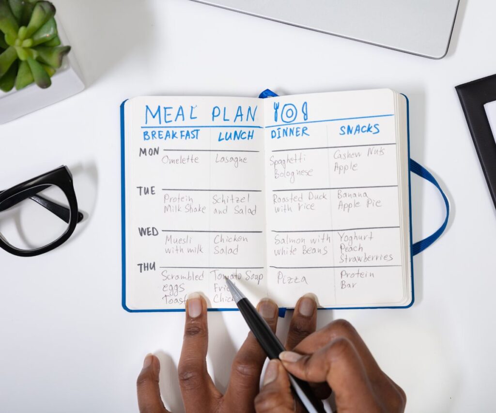 female working on the meal plan for the week in her notebook