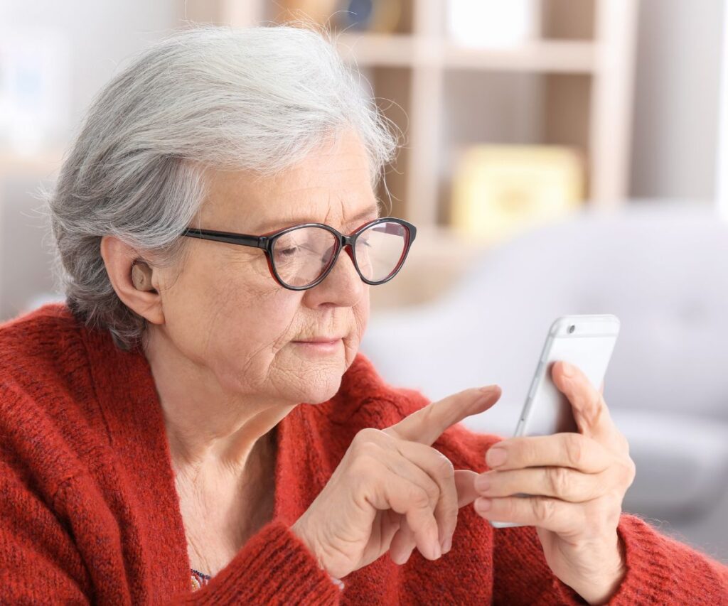 older woman with glasses and red sweater planning budget on her phone