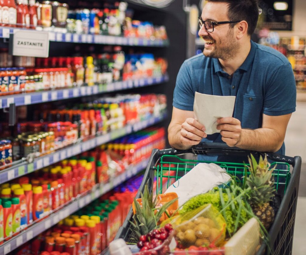 smiling man grocery shopping looking for spices he needs