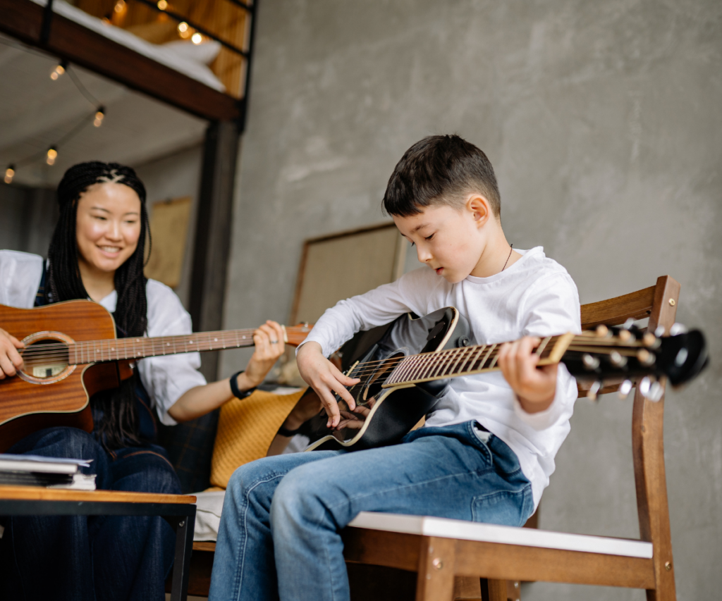 Woman and young boy learning to play guitar